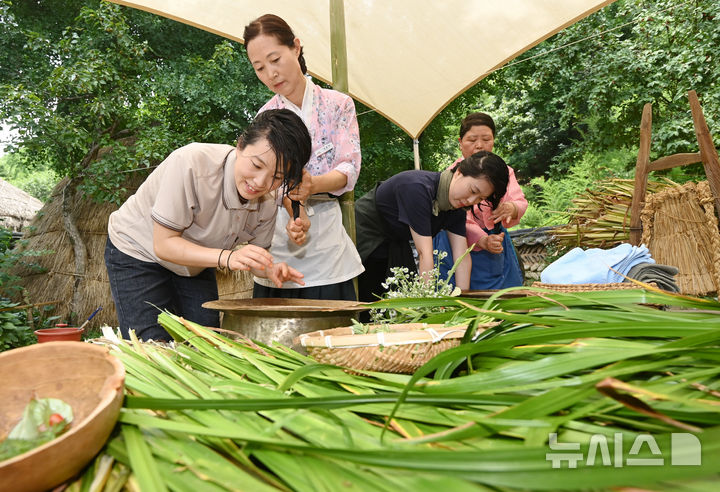[용인=뉴시스] 김종택 기자 = 단오를 하루 앞둔 18일 경기 용인시 한국민속촌에서 시민들이 창포를 삶은 물로 머리를 감는 세시풍속을 체험하고 있다. 2026.06.18. jtk@newsis.com