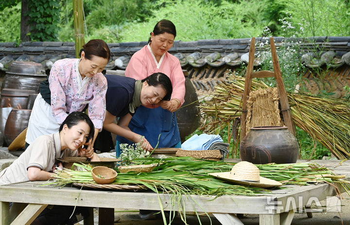 [용인=뉴시스] 김종택 기자 = 단오를 하루 앞둔 18일 경기 용인시 한국민속촌에서 시민들이 창포를 삶은 물로 머리를 감는 세시풍속을 체험하고 있다. 2026.06.18. jtk@newsis.com