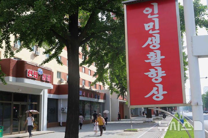 [평양=AP/뉴시스] 북한 여성 노동자들의 러시아 취업 광고가 등장한 가운데 지난 6월 22일 북한 평양 중앙 구역에서 시민들이 거리를 걷고 있다. 거리에는 "위대한 우리 국가의 번영을 위해 힘차게 노력하자!"라고 적힌 선전 포스터가 걸려 있다. 2026.06.22.