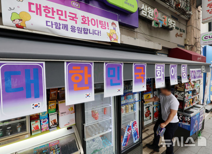 [서울=뉴시스] 조성우 기자 = 2026 북중미 월드컵 거리응원으로 서울 광화문광장 인근 편의점들이 특수를 누렸다. 유통업계에 따르면 한국 대표팀 경기가 열린 지난 19일 서울시 추산 약 1만8000명이 광화문광장에 모이면서 인근 편의점의 얼음·생수·맥주·안주류 등의 매출이 급증했다. 사진은 22일 서울 종로구 광화문광장 인근 편의점에 설치된 월드컵 관련 홍보물. CU는 광화문 인근 10여 개 점포 매출이 전일 대비 약 4배 늘었고, GS25는 138% 증가했다. 세븐일레븐도 광화문 인근 10개 매장의 19일 오전 9시부터 오후 2시까지 매출이 전일 대비 304% 증가했으며, 이마트24는 최대 38% 늘었다. 2026.06.22. xconfind@newsis.com