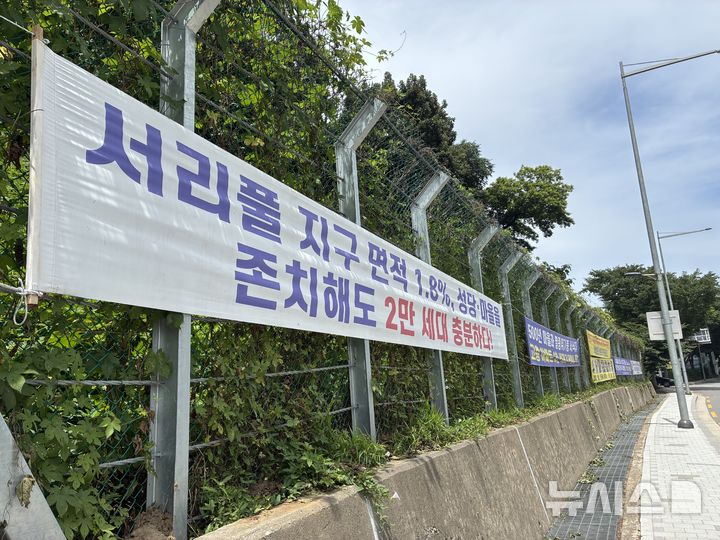 [서울=뉴시스] 윤도영 인턴기자= 24일 서울 서초구 우면동 성당 인근 길목에 서리풀2지구 개발에 반대하는 내용의 현수막이 붙어 있다. 이날 송동마을·식유촌마을 주민들과 성당 관계자들은 우면산 성당에서 기자간담회를 열어 서리풀2지구 사업 반대 입장을 냈다.2026.06.24.