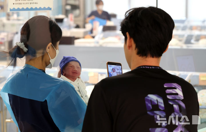 [고양=뉴시스] 전진환 기자 = 경기 고양시 CHA의과학대학교 일산차병원 신생아실에서 한 아빠가 자신의 아이의 사진을 찍고 있는 모습. 2026.06.24. amin2@newsis.com
