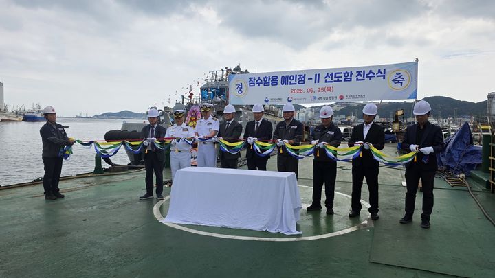 [서울=뉴시스] 25일 부산 동일조선에서 개최된 잠수함용 예인정-Ⅱ 사업 선도함 진수식에서 주요 참석자들이 오색 테이프를 절단하며 선도함의 안전항해를 기원하고 있다. (사진=방위사업청 제공) 2026.06.25. photo@newsis.com *재판매 및 DB 금지