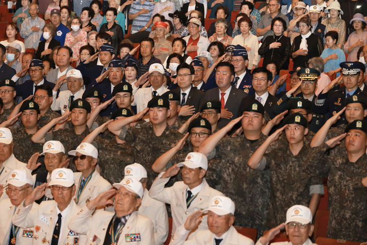 [청주=뉴시스] 25일 충북도와 청주시가 청주 예술의전당에서 개최한 6·25전쟁 76주년 기념행사에서 6·25 참전유공자와 군 장병, 보훈단체 회원, 기관단체장 등이 국기에 대한 경례를 하고 있다. (사진= 충북도청 제공) 2026.06.25. photo@newsis.com *재판매 및 DB 금지