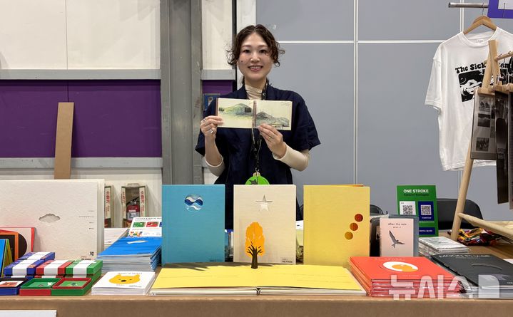 [서울=뉴시스] 한이재 기자 = 25일 도서전 책마을 내 'one storke' 부스에서 만난 아이 코마가타(Ai KOMAGATA)가 아버지 카츠미 코마가타(Katsumi KOMAGATA)의 사후 출판한 책 '스케치 온 저니(sketch on journey)'를 들어 보이고 있다. 2026.06.25. nowone@newsis.com