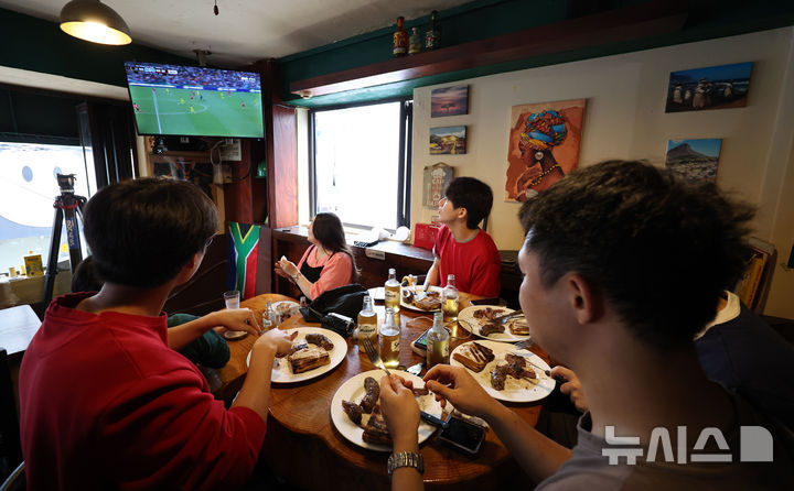 [서울=뉴시스] 김선웅 기자 = 25일 서울 용산구 이태원 소재 남아공 음식점 브라이리퍼블릭에서 내외국인들이 2026 중남미 월드컵 대한민국과 남아프리카 공화국의 경기 중계 방송을 시청하며 식사를 하고 있다. 2026.06.25. mangusta@newsis.com