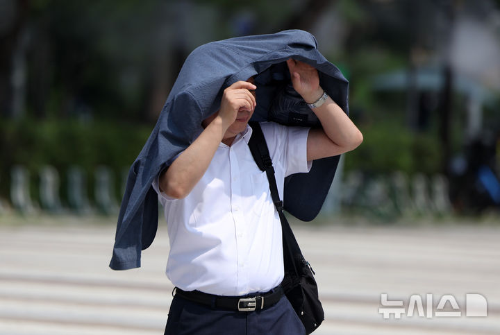 [서울=뉴시스] 김선웅 기자 = 낮 최고기온이 30도를 웃돈 30일 서울 종로구 청와대 앞 분수대 광장에서 한 시민이 옷으로 햇빛을 가리며 걷고 있다. 2026.06.30. mangusta@newsis.com