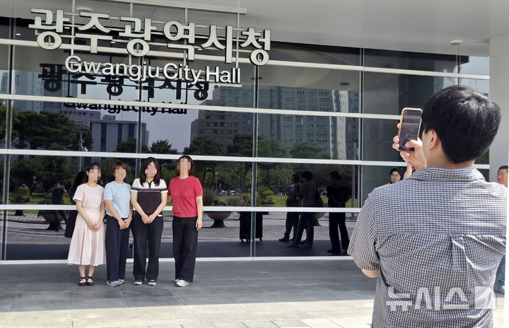 [광주=뉴시스] 30일 오전 광주 서구 광주시청사 1층 입구에 설치돼 있는 '광주광역시' 현판 앞에서 직원들이 기념사진을 찍고 있다. 현판은 이날 철거되고 '전남광주통합특별시'로 교체된다. 2026.06.30.hgryu77@newsis.com