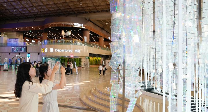 [서울=뉴시스] 김포공항 국제선 3층 일반대합실 로비에 설치된 이지연 작가의 ‘얼룩무지개숲’ 작품을 공항 이용객이 감상하고 있다. 2026.07.01. (사진=한국공항공사 제공) photo@newsis.com *재판매 및 DB 금지