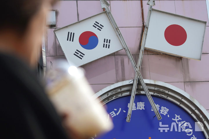 [도쿄=AP/뉴시스] 84년 전 발생한 일본 조세이 해저탄광 수몰 사고의 진상 규명을 요구하는 목소리가 커졌다. 일본 시민단체와 유족들은 일본 정부가 직접 유골 수습과 DNA 감정에 적극적으로 나서야 한다고 촉구했다. 시민단체 '조세이 탄광 수몰 사고를 역사에 새기는 모임'(이하 모임)은 지난달 30일 일본 참의원 의원회관에서 기자회견을 열고 이같이 밝혔다. 사진은 2019년 8월2일 일본 도쿄 신오쿠보 지역의 한 상점 앞에서 한 여성이 한국과 일본 국기가 그려진 광고판을 지나는 모습. 2026.07.01.