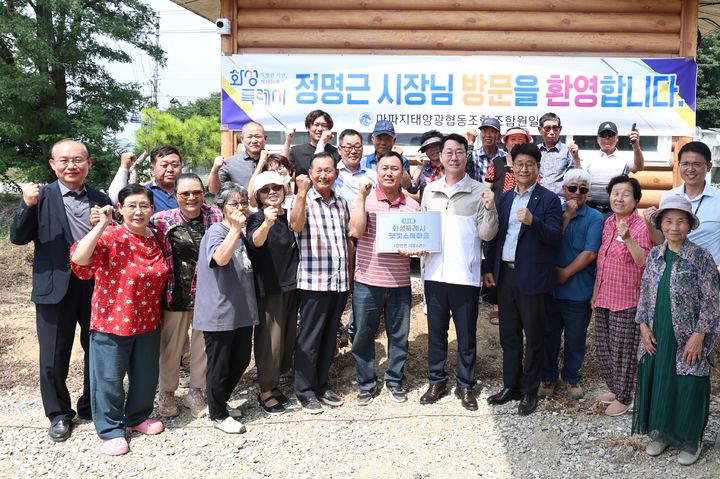 [화성=뉴시스] 정명근 화성시장(사진 앞줄 오른쪽에서 다섯 번째)이 1일 제1호 화성특례시 햇빛소득마을에 현판을 전달한 후 주민들과 함께 기념촬영을 하고 있다. (사진=화성시 제공) 2026.07,01. photo@newsis.com *재판매 및 DB 금지