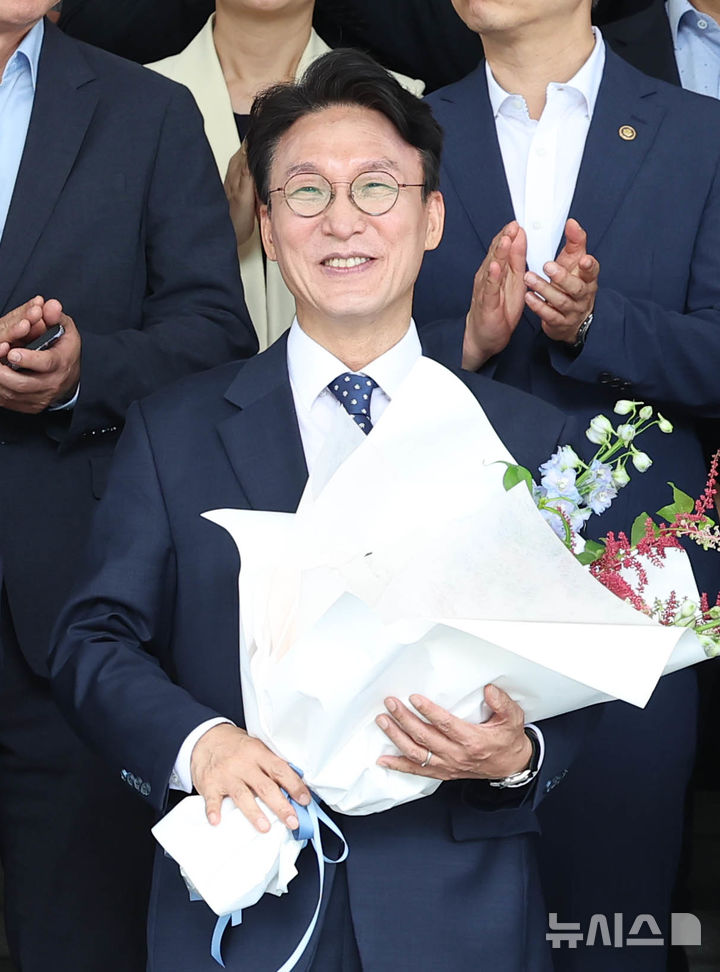 [서울=뉴시스] 조수정 기자 = 김민석 국무총리가 1일 오전 서울 종로구 정부서울청사에서 열린 제49대 국무총리 이임식을 마친 뒤 청사 앞에서 직원에게 꽃다발을 받고 기념촬영 하고 있다. 2026.07.01. chocrystal@newsis.com