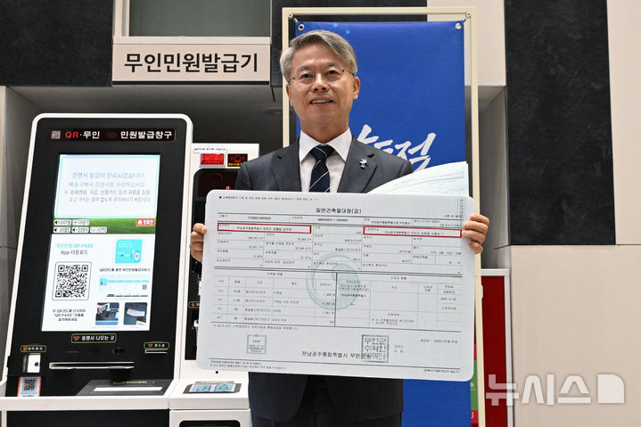 [무안=뉴시스] 이영주 기자 = 민형배 전남광주통합특별시장이 1일 오전 전남광주 무안군 전남광주통합특별시 남악청사에 설치된 무인민원발급기 앞에서 출력된 건축물대장을 들어보이면서 기념사진을 촬영하고 있다. 건축물대장에는 남악청사의 주소지가 기존 '전라남도 무안군 삼향읍'에서 '전남광주통합특별시 무안군 삼향읍'으로 변경돼있다. 2026.07.01. leeyj2578@newsis.com