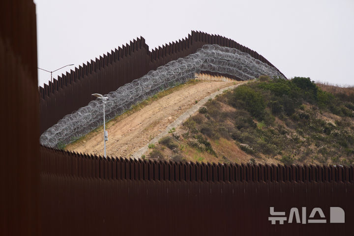 [샌디에이고 =AP/뉴시스] 미국 남부 국경의 티후아나 멕시코 관문 부근의 국경장벽이 2025년 6월 4일 완공되어, 미국 쪽에서 국경 장벽 내부와 강철 가시철조망이 설치된 상단의 광경이 관측되고 있다. 2026. 08.06. . 
