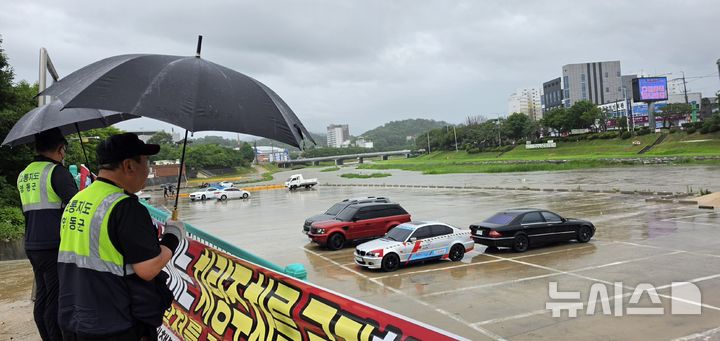 [영동=뉴시스] 연종영 기자 = 충북 영동군청 소속 직원들이 7일 오전 영동읍 영동천 하상주차장 출입을 통제한 후 전날부터 주차돼 있는 차량을 견인조치하고 있다. 기상청은 이날 오전 8시20분을 기해 영동지역에 대한 호우주의보를 호우경보로 격상했다. 2026.07.07. jyy@newsis.com
