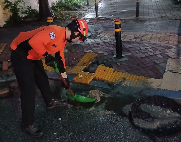 [익산=뉴시스] 아침부터 전북에 많은 비가 내린 7일 오전 6시50분께 전북 익산시 망성면의 한 인도 인근 배수구가 막혔다는 신고가 들어와 소방대원이 배수조치를 시행하고 있다. (사진=전북도소방본부 제공) 2026.07.07. photo@newsis.com *재판매 및 DB 금지