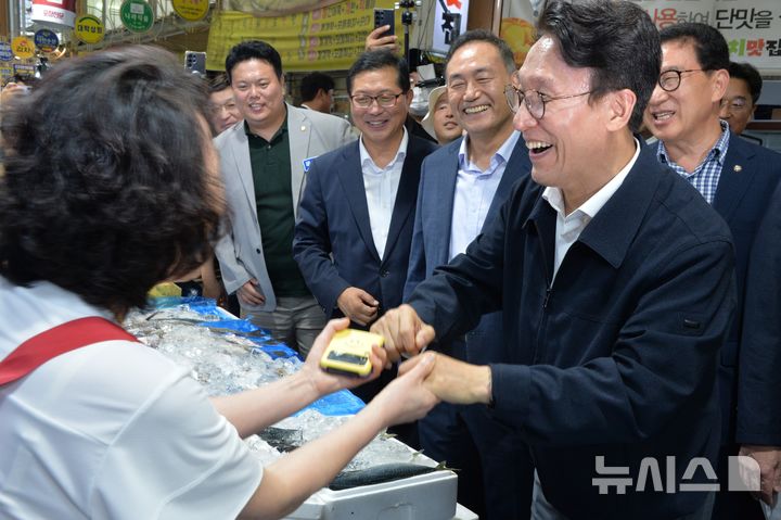 [목포=뉴시스]박상수 기자 = 8일 오후 전남광주 목포시 동부시장을 찾은 김민석 전 국무총리가 생선가게 상인과 손을 잡으며 웃고 있다. 2026,07.08. parkss@newsis.com