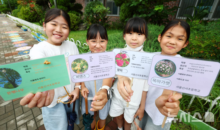 [서울=뉴시스] 전신 기자 = 8일 '2026년도 환경교육 우수학교'에 지정된 서울 양천구 서울신서초등학교에서 진행된 '식물 이름표 달아주기 대작전' 수업에서 학생들이 직접 만든 이름표를 들고 밝게 웃고 있다. 2026.07.08. photo1006@newsis.com