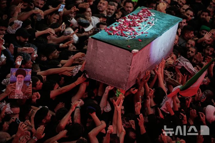 [AP/뉴시스] 알리 하메네이의 관이 9일 이란 안장지로 되돌아가기 직전 새벽 이라크 시아파 성지 카르발라의 임만 후세인 사원에서 만지기 위해 손을 뻗치는 애도자들 위로 움직이고 있다 