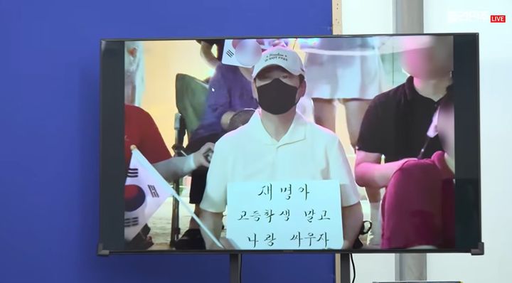 한병도 더불어민주당 대표 직무대행 겸 원내대표가 9일 국회에서 열린 정책조정회의에서 TV 화면을 통해 흰색 모자와 검은색 마스크를 착용한 채 태극기와 손팻말을 들고 있는 한 사람의 모습을 공개했다. 한 대행은 이 사람을 '장동혁 국민의힘 대표'라고 주장했다. (사진=더불어민주당 공식 유튜브 채널 '델리민주' 화면 캡처) *재판매 및 DB 금지