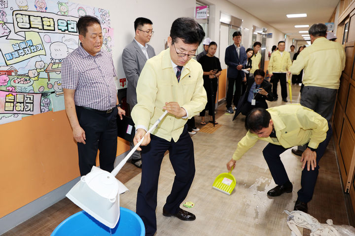 윤건영 충북도교육감(가운데)이 9일 집중호우로 침수피해를 본 청주 용아초 교실 복도에서 빗물 제거 작업을 하고 있다.(사진=충북교육청 제공).2026.07.09.photo@newsis.com *재판매 및 DB 금지