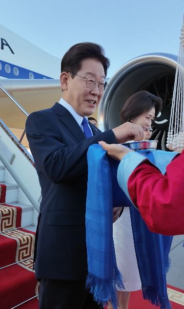 [서울=뉴시스] 이재명 대통령이 9일(현지시간) 몽골 울란바타르 칭기즈칸 국제공항에서 환영객이 건넨 몽골 전통 간식 '아롤(Aaruul)'을 맛보고 있다. (사진='Jaemyung_Lee' X 계정 캡처)