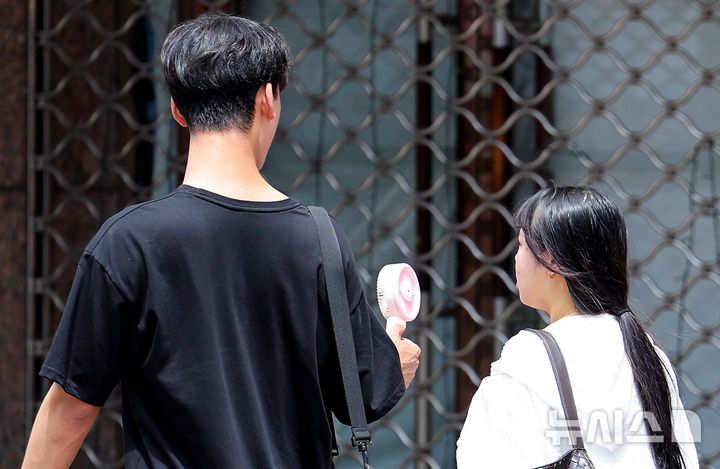 [대구=뉴시스] 이무열 기자 = 대구 낮 최고기온이 34도까지 오르며 더운 날씨를 보인 10일 대구 중구 동성로에서 한 시민이 손 선풍기를 들고 이동하고 있다. 2026.07.10. lmy@newsis.com