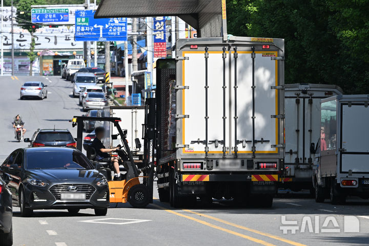 [전남광주=뉴시스] 이영주 기자 = 10일 오후 전남광주 북구 각화농산물공판장 주변 노상적치물 문제로 민원이 잇따르고 있는 도로에서 농산물 상하차 차량과 지게차, 통행 차량이 뒤엉켜있다. 2026.07.10. leeyj2578@newsis.com