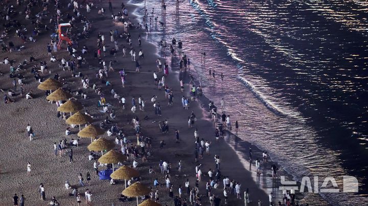  [부산=뉴시스] 하경민 기자 = 밤낮으로 푹푹 찌는 더위가 이어진 11일 밤 부산 수영구 광안리해수욕장에서 시민과 관광객들이 더위를 식히고 있다. 부산에는 지난 6일부터 폭염특보가 발효 중이며, 열대야도 지난 11일부터 이틀째 이어졌다. 2026.07.12. yulnetphoto@newsis.com