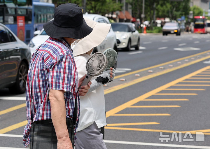 [서울=뉴시스] 이영환 기자 = 폭염이 이어지고 있는 12일 오후 서울 중구 세종대로에서 모자를 쓴 시민들이 손풍기를 들고 이동하고 있다. 2026.07.12. 20hwan@newsis.com