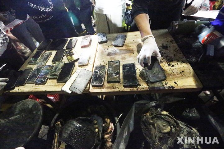 [방콕=신화/뉴시스] 13일(현지 시간) 태국 방콕의 한 술집 화재 현장에서 구조대와 경찰이 불에 훼손된 휴대전화기들을 수습해 정렬하고 있다. 12일 자정께 발생한 이 불로 최소 27명이 숨지고 63명이 다쳤으며 이 중 22명은 위독한 상태인 것으로 알려졌다. 2026.07.13.