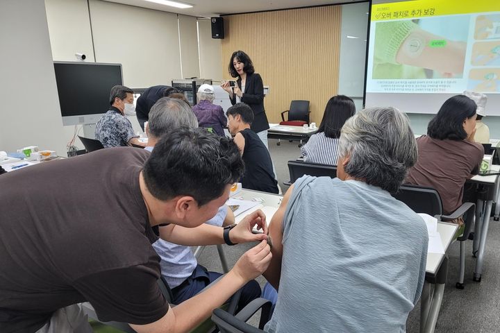 [서울=뉴시스] 올해 상반기 '시니어 지속가능 식생활 교육'에서 교육 담당자들이 참가자들에게 CGM 이용 방법에 대해 알려주고 있다. (사진=풀무원 제공) *재판매 및 DB 금지