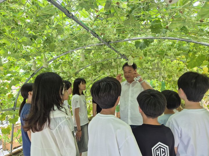 [울산=뉴시스] 구미현 기자 = 박영택 울산복산초 교장이 14일 교내 2층 공간에 조성한 덩쿨 터널에서 학생들에게 생태 환경교육을 하고 있다. 2026.07.14. gorgeouskoo@newsis.com *재판매 및 DB 금지
