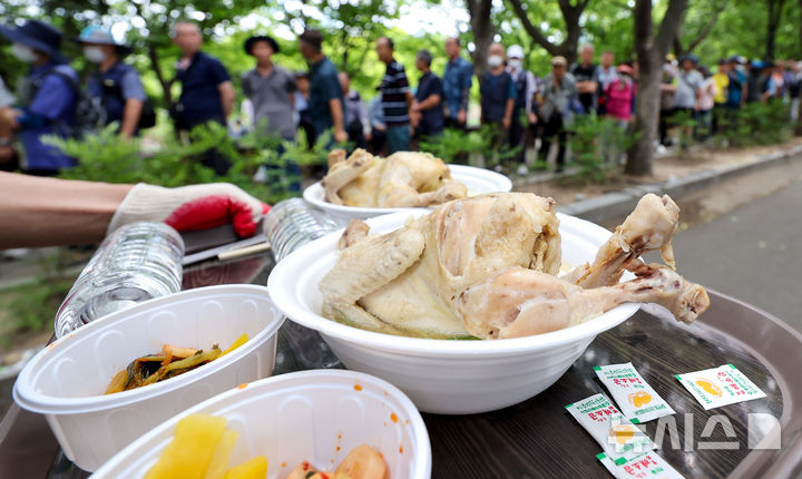 [대구=뉴시스] 이무열 기자 = 초복을 하루 앞두고 폭염이 연일 이어진 14일 대구 달서구 두류공원 사랑해밥차 무료급식소를 찾은 어르신들이 삼계탕을 받기 위해 줄을 서고 있다. 2026.07.14. lmy@newsis.com