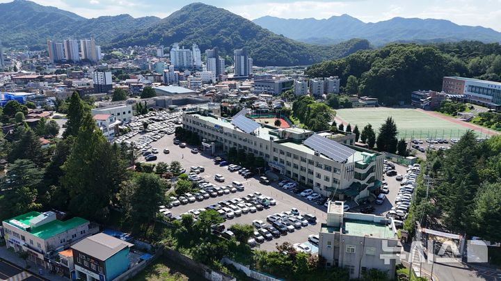 [옥천=뉴시스] 연종영 기자 = 15일 드론으로 부감 촬영한 충북 옥천군 본청과 주차장 전경. 군청사 뒤에 있는 학교는 옥천고교다. 옥천읍 삼양리에 자리 잡은 이 청사는 1978년 준공했다. 낡고 좁고 재난에 취약하다. 옥천군은 내년 2월 옥천읍 문정리에 신청사를 준공하고 그해 하반기에 신청사에 입주한다. 2026.07.15. jyy@newsis.com