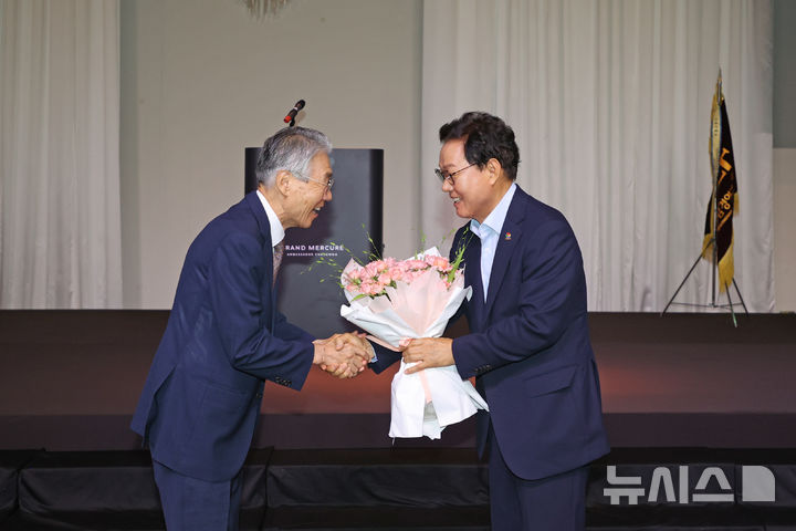 [창원=뉴시스]15일 오전 경남 창원 그랜드머큐어앰배서더 호텔에서 열린 경남경영자총협회 제341회 노사합동 조찬세미나에 참석한 박완수(오른쪽) 경남도지사가 이상연 경남경총 회장으로부터 재선 당선 축하 꽃다발을 받고 있다.(사진=경남도 제공) 2026.07.15. photo@newsis.com
