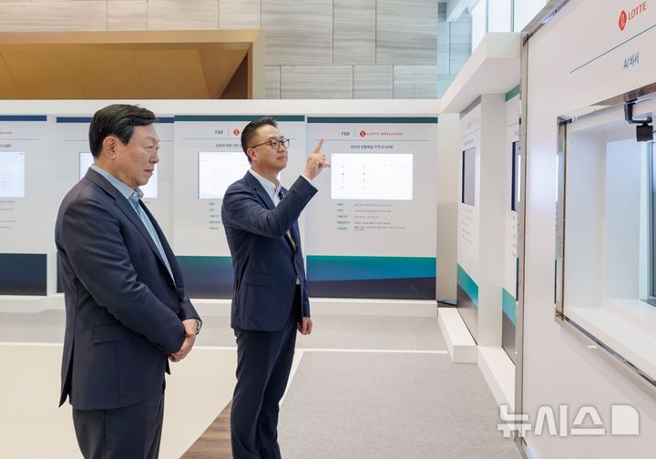 [서울=뉴시스] 롯데는 15일 롯데월드타워에서 '2026 하반기 VCM'을 개최했다. 회의에 앞서 신동빈 롯데 회장(왼쪽)이 황민재 롯데지주 경영혁신실장(오른쪽)으로부터 음성과 모션 인식 기반 'AI 비서'에 대한 설명을 듣고 있다. (사진=롯데 제공) 