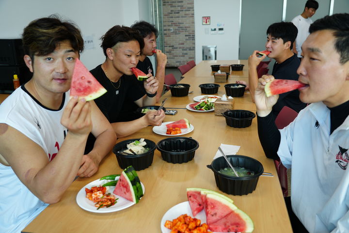 [울산=뉴시스] 초복인 지난 15일 문수야구장 구내식당에서 수박을 먹는 오카다, 고바야시, 설재욱, 조준혁, 통역 이기범 (사진=울산웨일즈 제공) 2026.07.16. photo@newsis.com *재판매 및 DB 금지