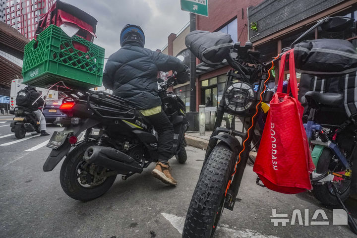 [샌프란시스코=AP/뉴시스] 미국 차량공유업체 우버가 독일 음식배달업체 딜리버리히어로를 약 125억유로(약 21조3000억원)에 인수하는 협상을 진행 중이다. 15일(현지시간) 파이낸셜타임스(FT)에 따르면 우버는 딜리버리히어로 주식을 주당 약 41유로에 인수하는 방안을 협의하고 있다. 사진은 음식 배달원이 2024년 1월29일 미국 뉴욕 브루클린 플랫부시 애비뉴의 패스트푸드 식당에서 음식을 받은 뒤 오토바이를 타고 이동하는 모습. 2026.07.16.