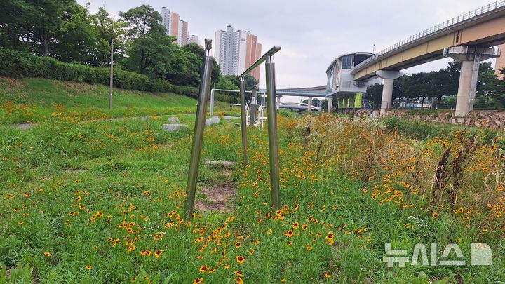 [김해=뉴시스]경남 김해시 도심 해반천에 설치된 운동기구 주변에 잡풀이 무성해 시민들이 불편을 겪고 있다. 2026.07.18. woo@newsis.com