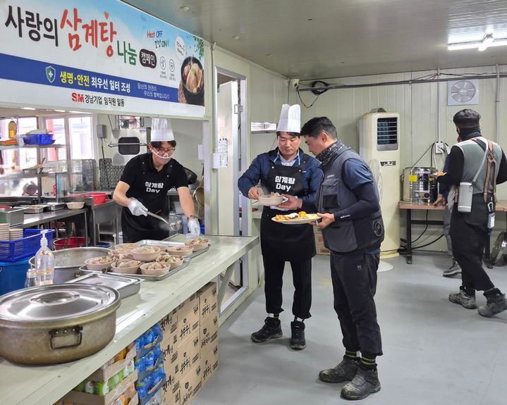 [서울=뉴시스] 경남기업 이기동 대표이사(사장, 맨 왼쪽)와 성유진 건축사업실장(상무, 왼쪽 두 번째)이 지난 16일 경기 양주시 양주 옥정 A-22블록(BL) 아파트 건설 1공구 현장에서 혹서기 온열질환 예방 캠페인의 일환으로 진행된 ‘삼계탕 Day’에 배식자로 나서 근로자들에 삼계탕을 나눠주고 있다. (제공=SM그룹) 2026.07.21. photo@newsis.com *재판매 및 DB 금지