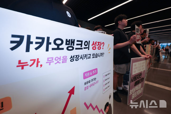 [성남=뉴시스] 김명년 기자 = 민주노총 화섬식품노조 카카오지회 조합원들이 21일 카카오뱅크가 입주한 경기 성남시 판교테크원에서 사측의 임금 인상률과 성과급 등 보상 체계를 규탄하는 피켓 시위를 하고 있다. 2026.07.21. kmn@newsis.com