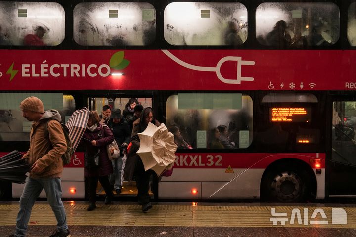 [산티아고=AP/뉴시스] 20일(현지시간) 칠레 산티아고에 비가 내리는 가운데 시민들이 버스에서 내리며 우산을 펴고 있다. 2026.07.20.