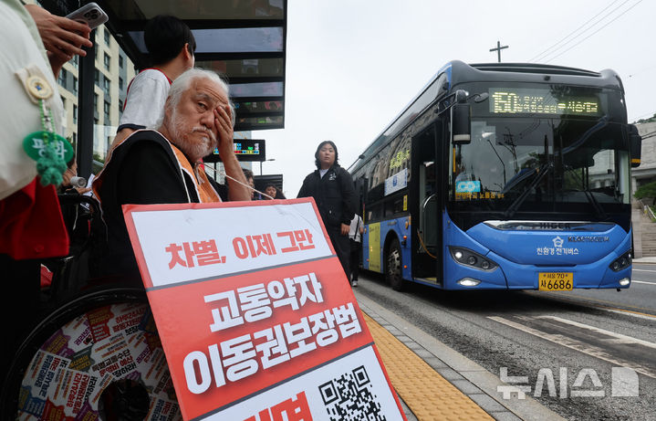 [서울=뉴시스] 권창회 기자 = 박경석 전국장애인차별철폐연대(전장연) 대표와 회원들이 7월 22일 오전 서울 종로구 혜화동로터리 버스정류장에서 교통약자이동권보장법 전면 개정 촉구 '출근길 버스탑니다' 시위를 하고 있다. 2026.07.22. kch0523@newsis.com