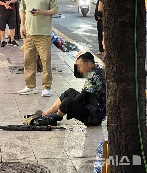 [서울=뉴시스] 23일 오후 서울 종로구의 한 건물 외벽에서 떨어진 콘크리트 파편에 머리를 맞은 60대 남성이 인도에 주저앉아 있다. 이 남성은 이후 두부출혈로 병원에 이송됐다. (사진=독자 제공) 2026.07.23. photo@newsis.com