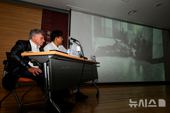 [전남광주=뉴시스] 이영주 기자 = 1980년 5월 광주의 참상을 세계에 알린 프랑스 출신 기자 '패트릭 쇼벨'(Patrick Chauvel·왼쪽)이 23일 오후 전남광주 동구 5·18기록관에서 열린 전남광주통합특별시 1호 명예시민증 수여식과 특강에 참석해 5·18 당시 찍은 사진을 설명하고 있다. 슬라이드 속 사진은 쇼벨이 촬영한 5·18 최후항전 당시 전일빌딩에서 계엄군에 붙잡힌 전일방송 직원들의 모습. 2026.07.23. leeyj2578@newsis.com