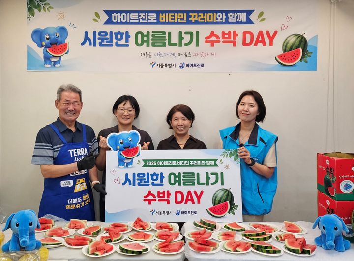 [서울=뉴시스] 22일 서울역 쪽방촌에서 2026 하이트진로 비타민 꾸러미와 함께 시원한 여름나기 '수박 DAY' 행사가 열렸다. (왼쪽부터) 쪽방촌 주민, 이신옥 서울시 팀장, 유호연 서울역 쪽방상담소 소장, 하이트진로 관계자가 기념 촬영을 하고 있다. (사진=하이트진로 제공) *재판매 및 DB 금지