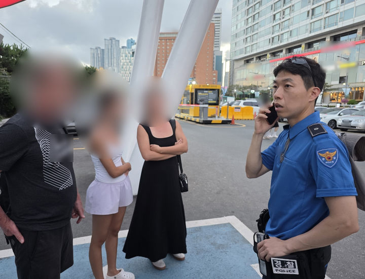 [부산=뉴시스] 부산 해운대해수욕장 인근에서 관광 중인 미국인 일가족을 돕고 있는 경찰관. (사진=부산경찰청 제공) 2026.07.24. photo@newsis.com *재판매 및 DB 금지