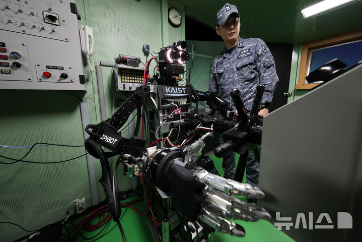 [창원=뉴시스] 사진공동취재단 = 23일 경남 창원 진해구 해군교육사령부 조함훈련장 시뮬레이터에서 진행된 ‘해상 당직업무 수행 로봇 전투실험’에서 한국과학기술원(KAIST)이 개발한 인간형 로봇(휴머노이드) ‘파이봇(PIBOT)’이 조타수 임무를 수행하고 있다. 2026.07.24. photo@newsis.com