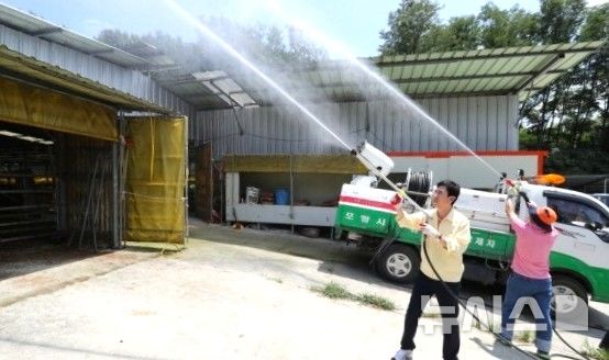 [포항=뉴시스] 포항시 직원과 농업인이 축사 주변 긴급 살수 작업. (사진=포항시 제공) 2026.07.27. photo@newsis.com
